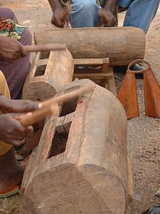 two African slit wooden drum hands holding mallets