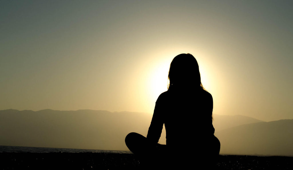 woman sitting and facing sunset