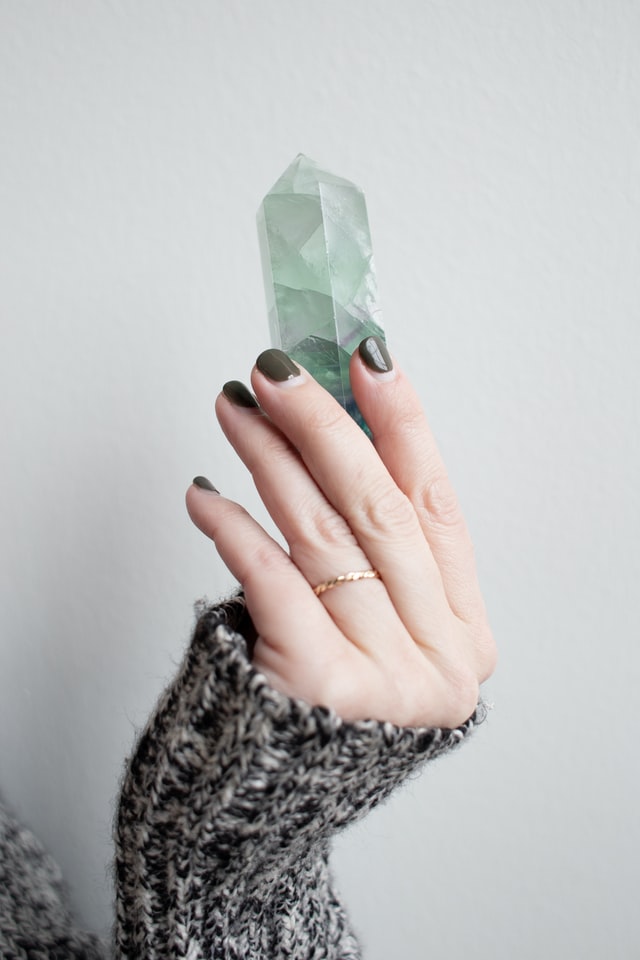 woman's hand green nail polish holding green crystal prism