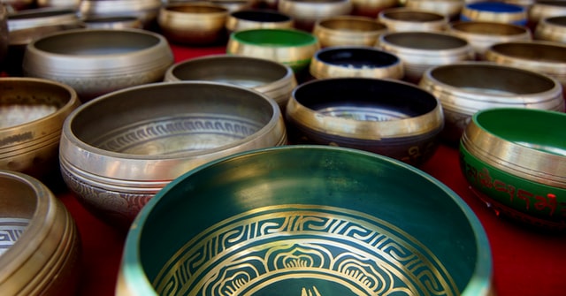 many pieces of different colored singing bowls spread on a red floor