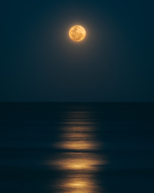 full moon over calm ocean evening horizon 