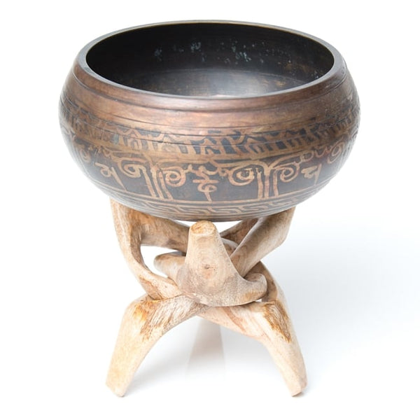 singing bowl with design placed on a wooden stand