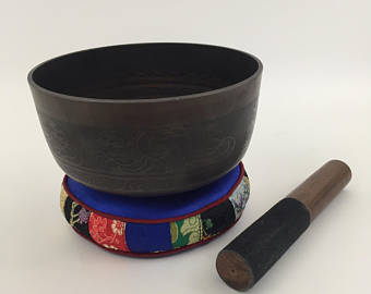 black singing bowl placed on a blue circle pillow