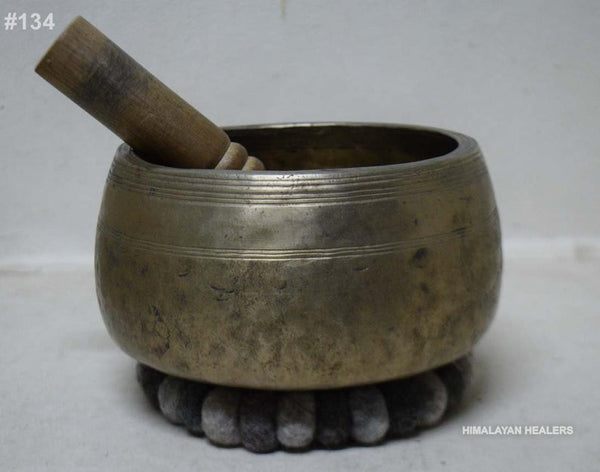 singing bowl with mallet inside placed on a gray felt cushion