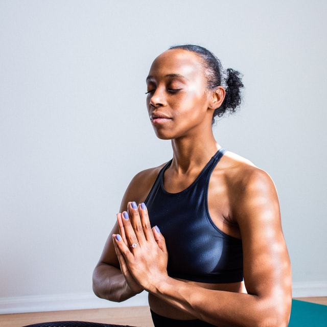 african woman hands in prayer pose near chest eyes closed