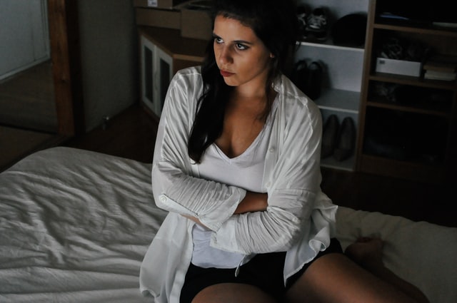 woman sitting on bed arms crossed appearing upset
