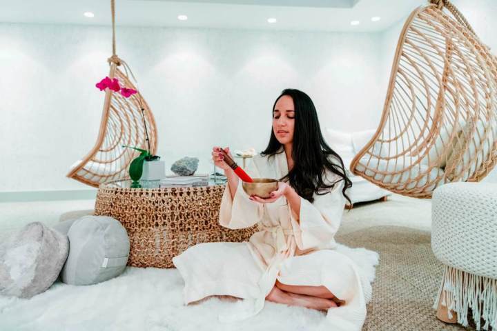 woman wearing white bathrobe playing singing bowl