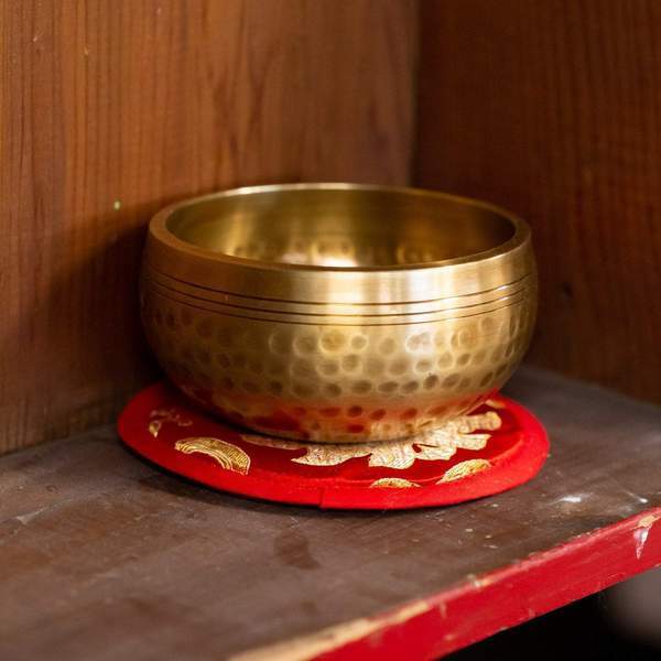 hammered singing bowl placed on a red circular mat with gold embroidery