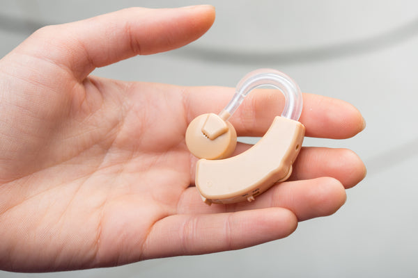 Beige hearing aid being held in a hand