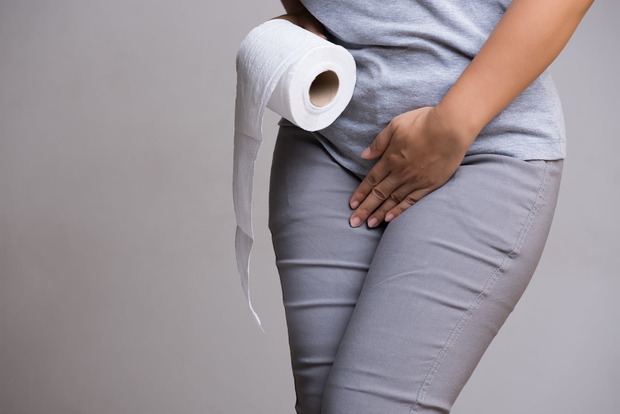 Woman crossing her legs holding a roll of toilet paper