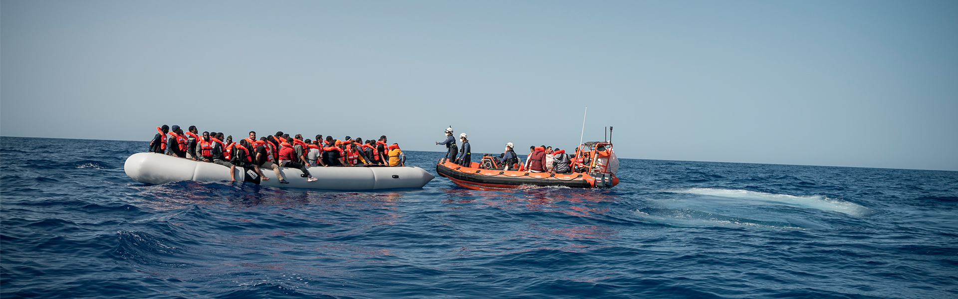 Ein Rettungsboot nähert sich auf dem Mittelmeer einem Schlauchboot mit Geflüchteten. | Copyright: Paul Lovis Wagner / Sea-Watch