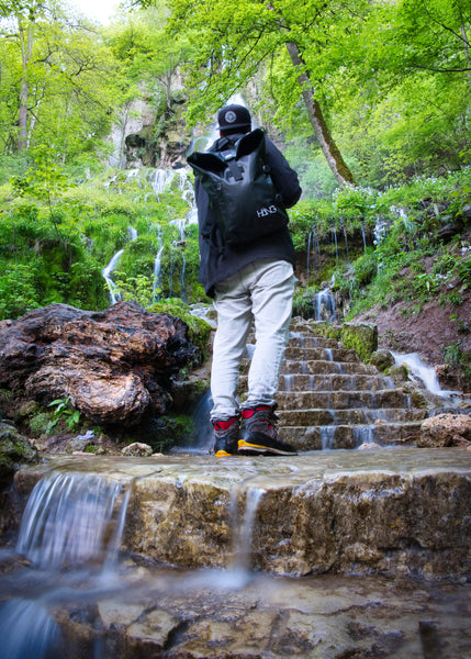 Mann mit schwarzem Rucksack auf der Schulter stehend im Wald 