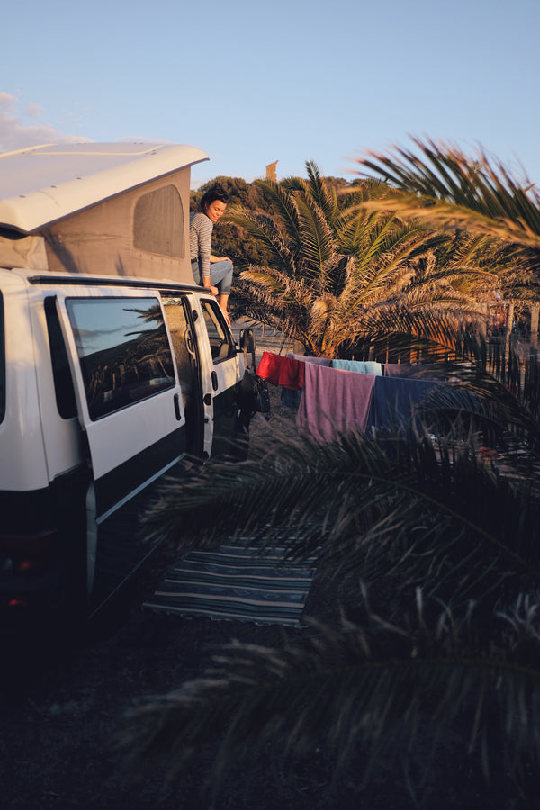 Frau bei Sonnenuntergang auf dem Dach eines Campers