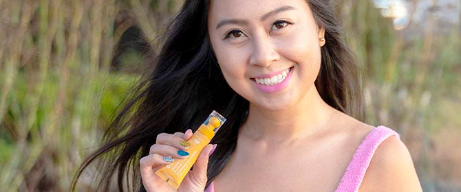 Mujer sosteniendo la crema para ojos con vitamina C afuera