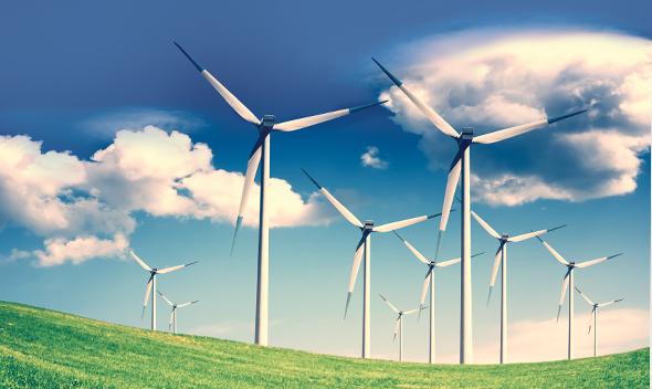 Windmill power generators in grass field with blue sky.