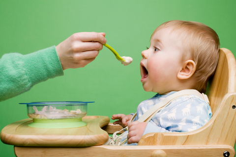 person feeding baby food