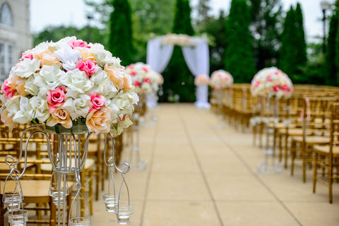 Links und rechts sind Stühle mit Blumendekoration aufgestellt. Zwischen den Stühlen verläuft in der Mitte ein Gang der das Brautpaar nach vorne führen wird.