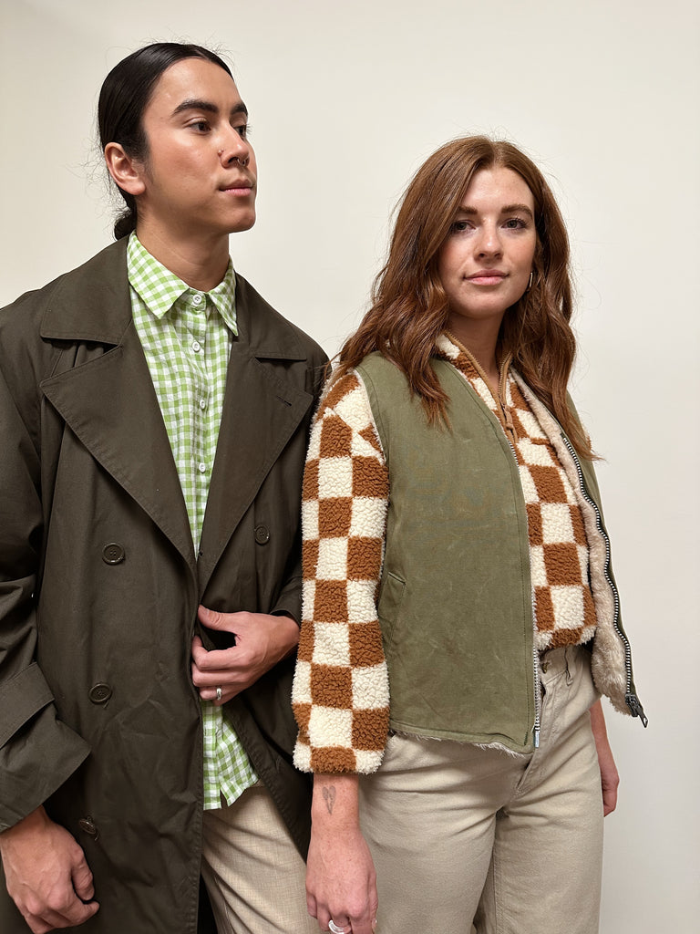 Two people stand wearing matching outfits featuring checkered clothes