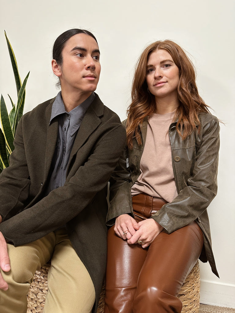 Two people sit wearing brown winter coats