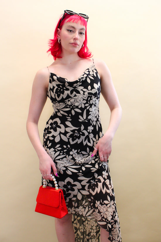 Woman with pink hair wears vintage black and white floral slip summer dress holding mini red purse