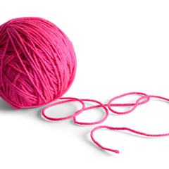 A pink tightly wound ball of yarn, illustrating the potential risks of causing strain and stretching fibers during storage when winding yarn too tightly.
