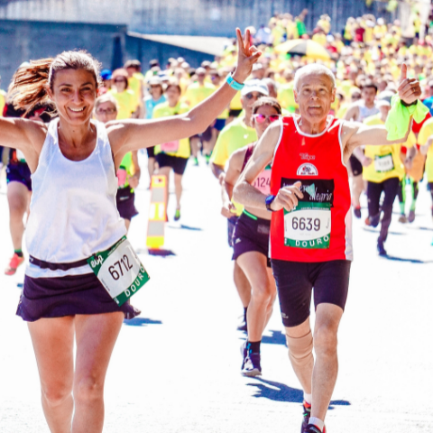 A woman crossing the finish line of a road race with a man about to finish behind her