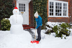 Person shoveling snow from walkway in front of a house