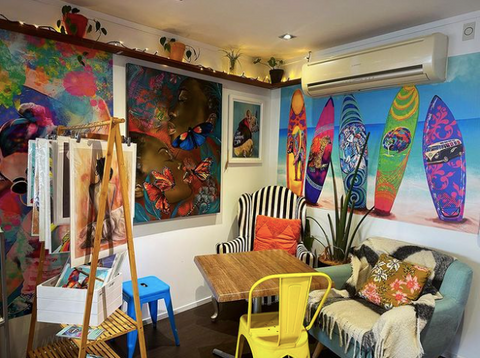 Colourful paintings and a bright yellow chair inside The Stoned Cow cafe