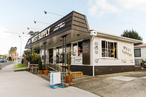 Outside view of West Supply and West Supply Coffee. There is a Kōkako foothpath sign in the foreground.