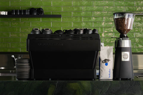 Green tiled wall with a black coffee machine