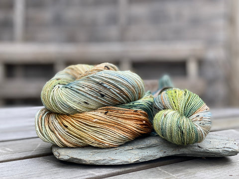 A curled up skein and matching twisted up skein on a piece of slate