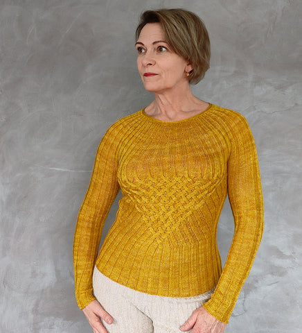 A person wearing a rich yellow coloured cable knit sweater