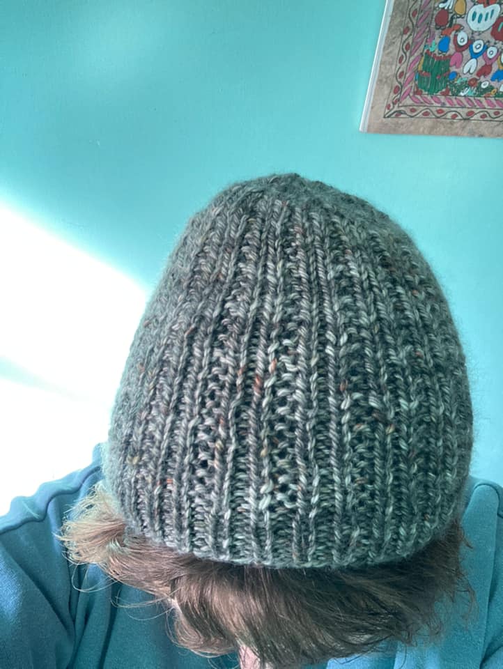 Alison wearing a blue/grey hat with textured stitches running the height of the hat