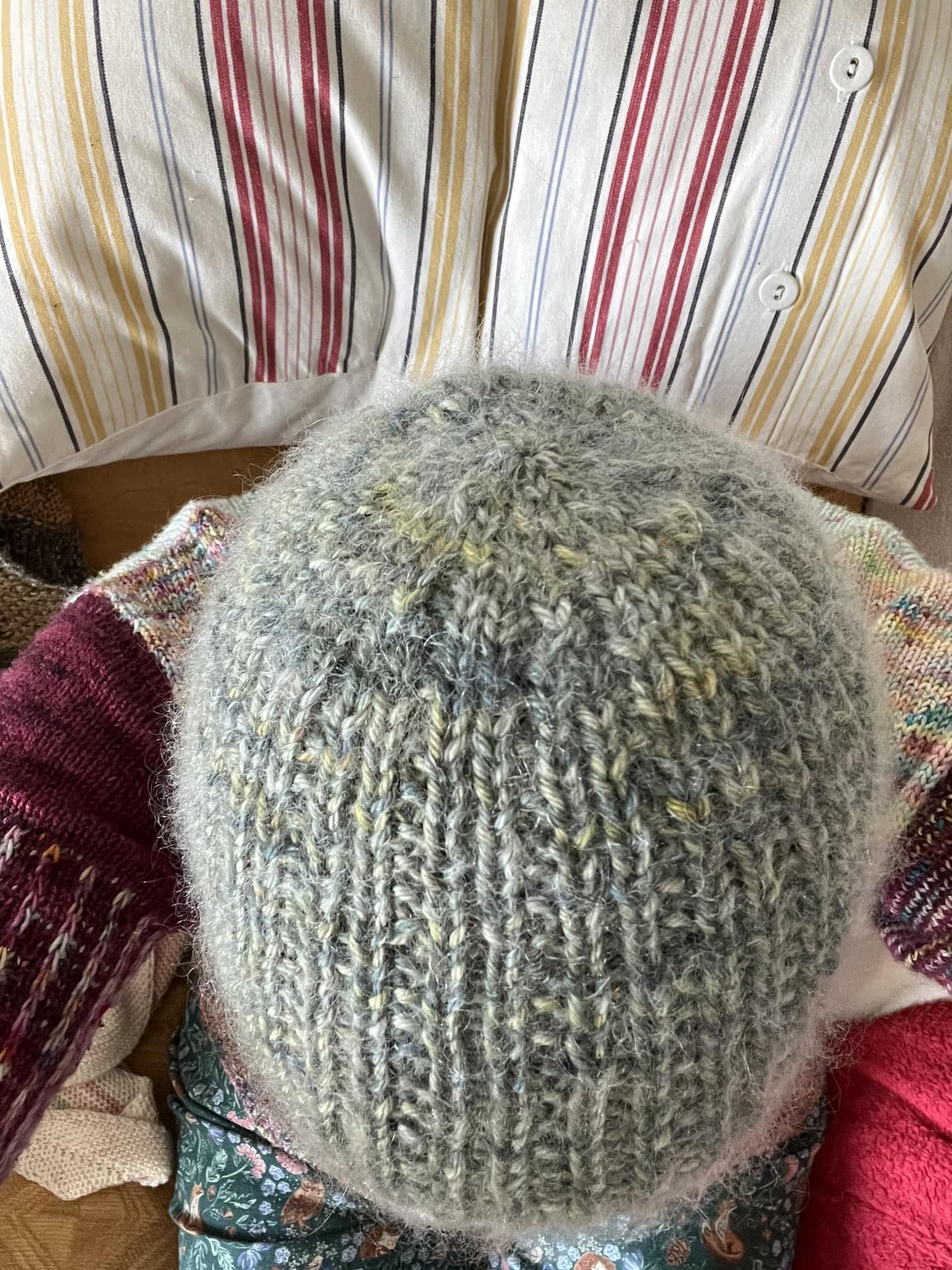 A view from above of a fuzzy knitted hat being modelled. The hat is blue, grey and green