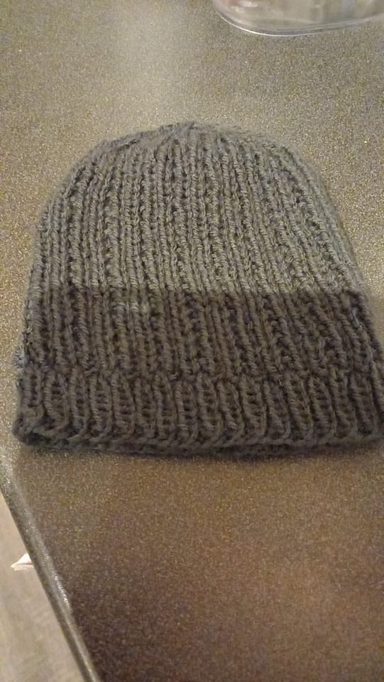 A grey knitted hat resting on a grey surface