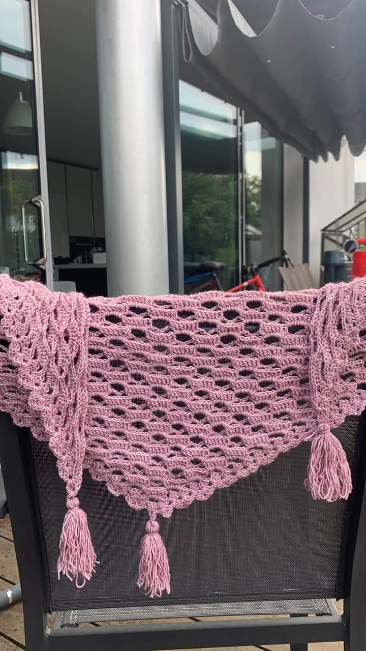 A pink lace shawl draping over the back of a chair