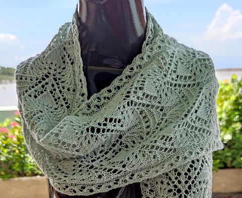 A pale grey-blue lace scarf wrapped around a black form