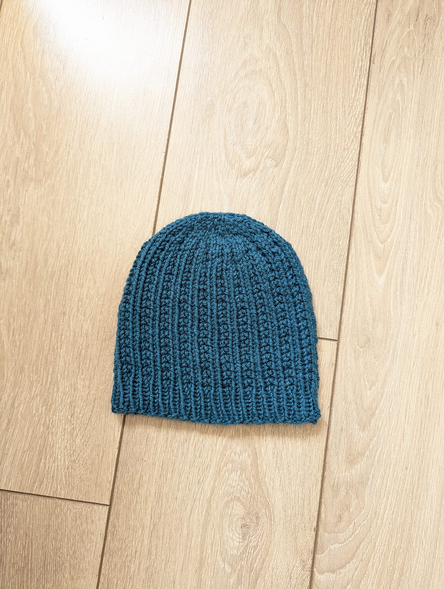 A blue knitted hat on a beige surface
