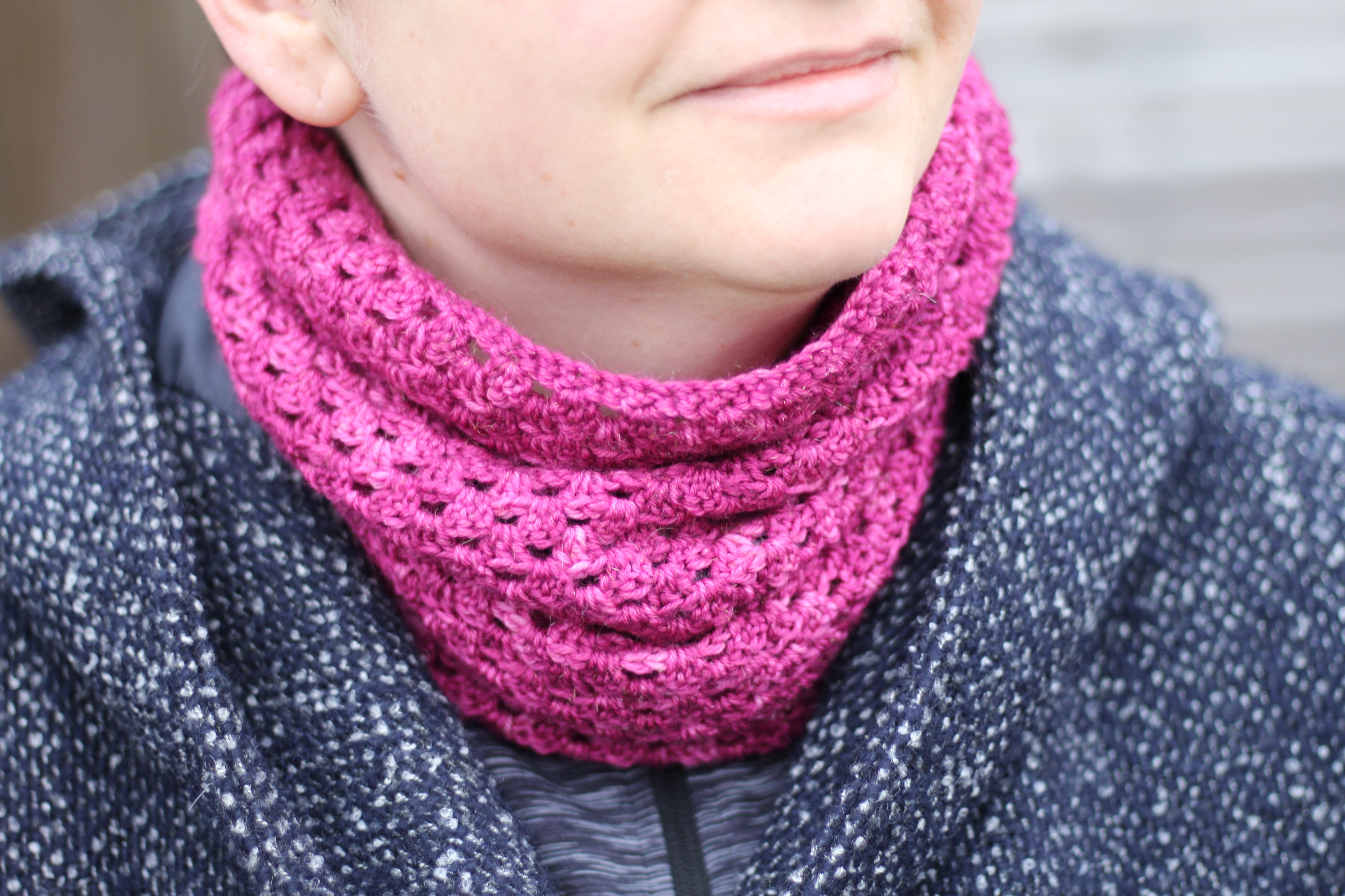 Victoria wearing a rich pink crochet cowl with a black and white coat