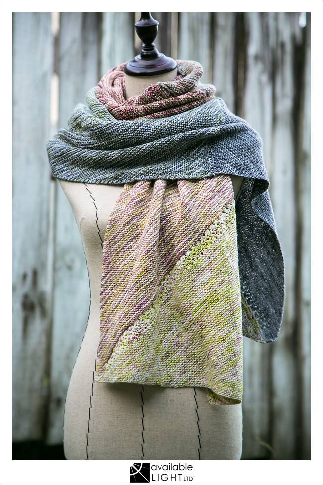 Rectangular wrap draped around a mannequin. The wrap features triangular sections of muted tweedy colours.