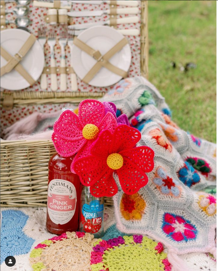 A picnic scene featuring various crocheted items in bright colours