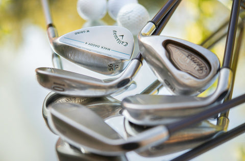 demo golf clubs standing with some golf balls in a mirroed surface