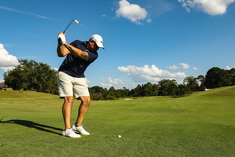 Golf player swinging a golf club in a golf course