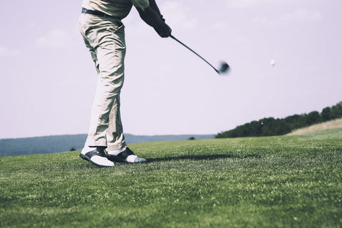 golfer swinging golf club to tee off golf ball in a golf course