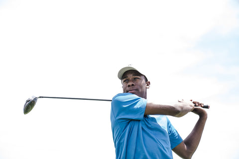 golfer holding a golf clubs with the golf shaft over his shoulder