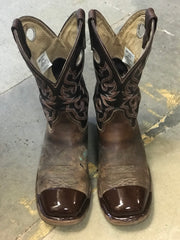 Pair of brown cowboy boots with intricate embroidery on the shafts and TUFF TOE applied on the glossy toe caps, displayed on a concrete floor.