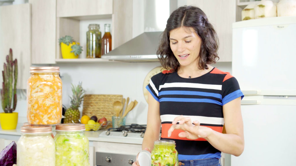 woman in striped shirt with fermented foods in a jar