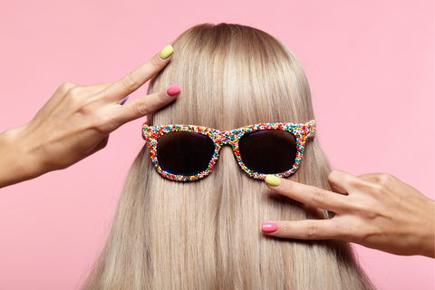 blonde with sunglasses on her hair gesturing a peace sign