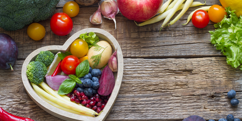 a heart shaped bowl filled with fruit and vegetables 