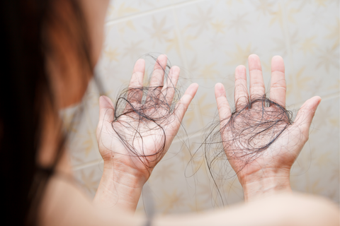 woman holding black hair in her hands in the shower